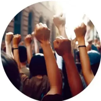 Fotografía de brazos levantados con puños en alto durante una protesta o manifestación, con luz cálida.