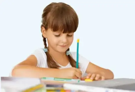 Fotografía de una niña de cabello castaño con trenzas, sentada escribiendo con un lápiz sobre un cuaderno.