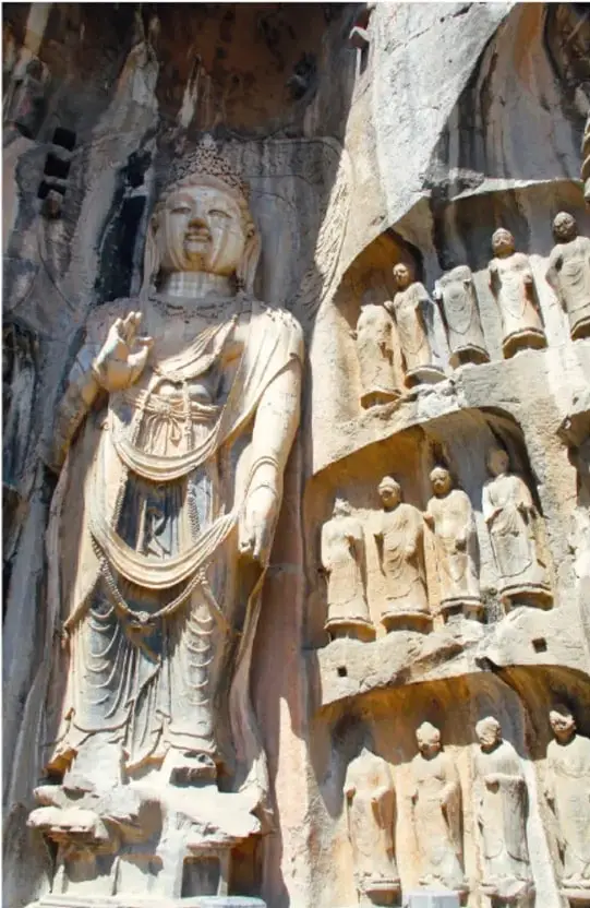Relieve rupestre con un gran Buda de pie y varias figuras humanas talladas en la roca, propio del arte budista chino.