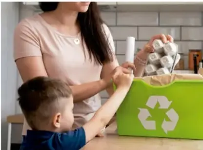 Mujer y niño depositando botellas de plástico en un contenedor verde de reciclaje.