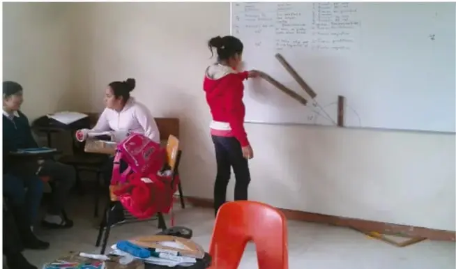 Fotografía de estudiantes en el aula trabajando con material geométrico frente al pizarrón (crédito: Jesús Eduardo Arteaga Fuentes, INALI PM).