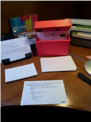 Escritorio con cuadernos, notas y una caja roja; materiales de trabajo escolar.