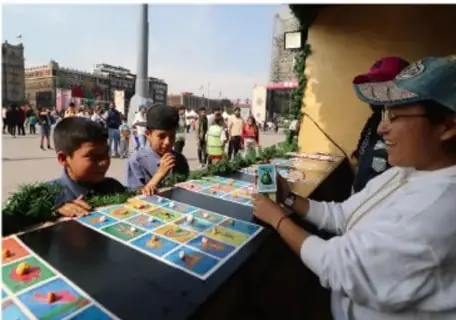 Grupo de niñas y niños jugando un juego de mesa al aire libre en un espacio público, con una adulta acompañando.