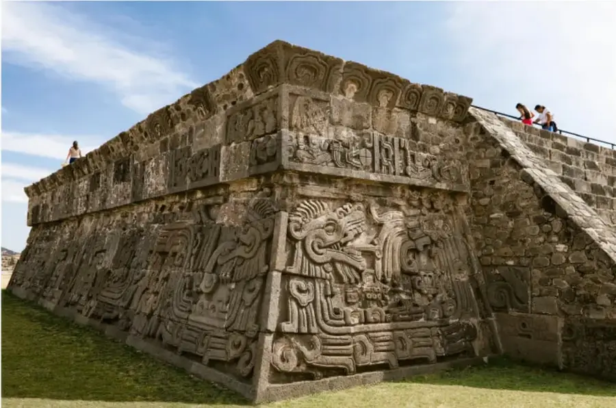 Fotografía de una pirámide prehispánica con rica ornamentación escultórica (serpiente emplumada y relieves), probablemente de Tollan-Xicotencatl o zona arqueológica similar, con visitantes en la escalinata, ilustrando el estudio de pueblos antiguos.