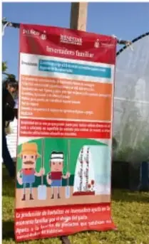 Pancarte rojo instalado al aire libre con la información de un proyecto comunitario (mercadito o programa local) e ilustraciones de personas; el texto pequeño no es legible con certeza.