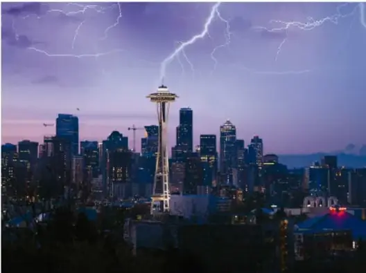 Fotografía nocturna de una ciudad con la Space Needle de Seattle y un rayo cayendo en el fondo.