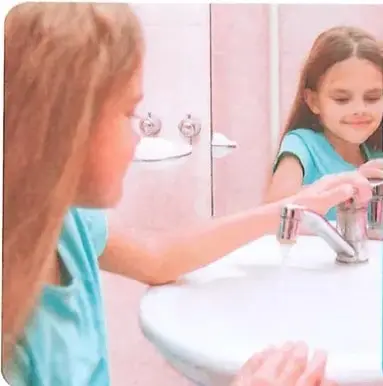 Una niña cierra la llave de agua mientras se lava las manos.
