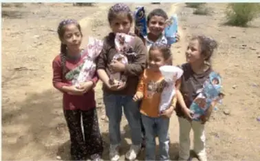 Fotografía a color de un grupo de niñas y niños sonrientes en un entorno al aire libre, vistiendo ropa casual, como símbolo de la niñez actual.