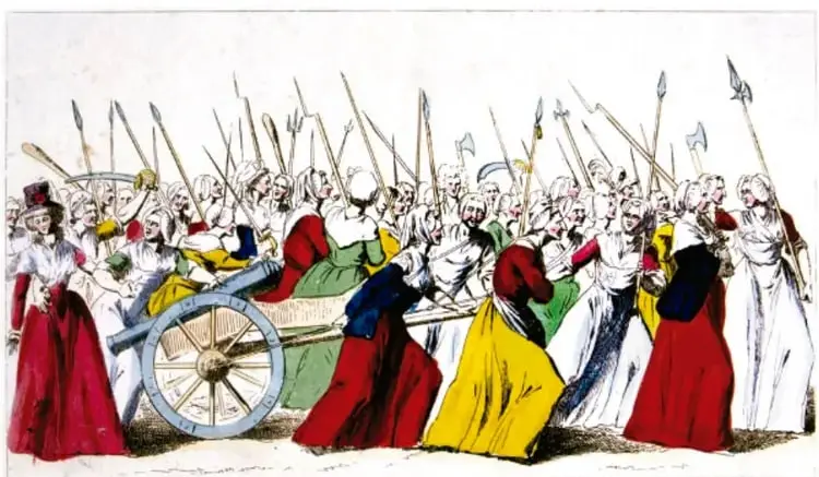 Grabado coloreado titulado 'La Marcha de las mujeres a Versalles, 5 de octubre de 1789', anónimo, Biblioteca Nacional de Francia. Muestra a un grupo de mujeres armadas con picas empujando un cañón, dirigidas hacia Versalles.