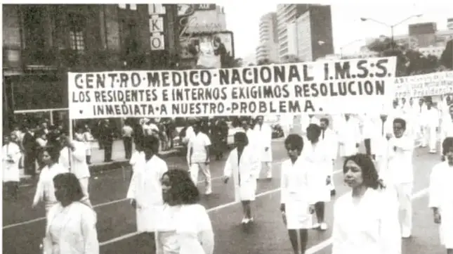 Fotografía en blanco y negro de una marcha de médicos y residentes del Centro Médico Nacional IMSS, con pancartas que exigen solución inmediata a su problema.