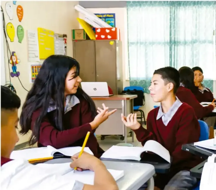 Fotografía de estudiantes en el aula conversando y tomando notas durante el desarrollo del proyecto.