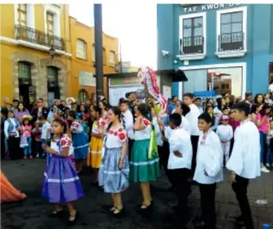 Grupo de niños y niñas en un acto escolar al aire libre.