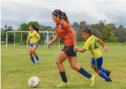 Personas practicando fútbol en una cancha al aire libre.