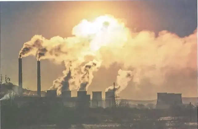 Fotografía de chimeneas industriales que emiten humo y contaminan el aire. El pie de imagen relaciona estas emisiones con el aumento de los gases de efecto invernadero.