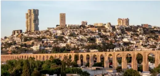 Fotografía actual de una ciudad con edificios modernos y un acueducto de arcos, ilustrando los cambios en el espacio y en las comunidades.