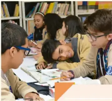 Fotografía de estudiantes en una biblioteca leyendo y compartiendo libros.