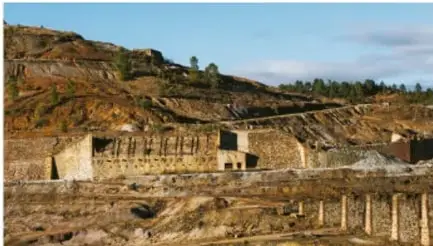 Fotografía de una mina a cielo abierto con excavaciones y terreno deforestado, ilustrando la extracción intensiva de materias primas.