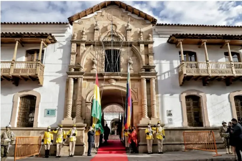 Fotografía de un edificio histórico colonial con banderas y guardia de honor en la entrada, probablemente un palacio de gobierno.
