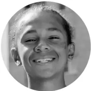 Fotografía en blanco y negro de una niña sonriente, estudiante de primaria.