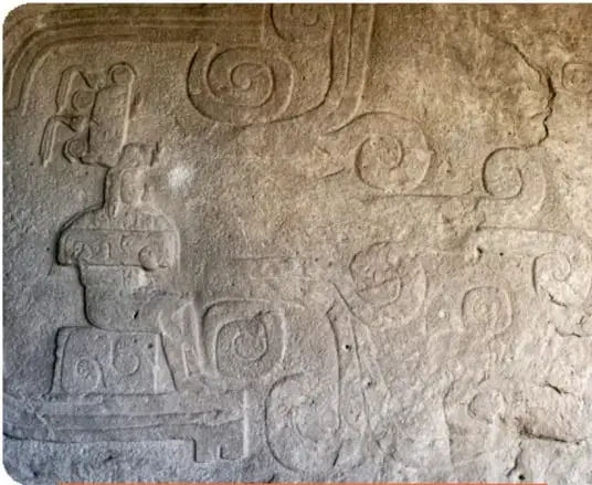 Relieve que muestra la figura sedente de un hombre dentro de una cavidad o cueva, con agua brotando en el centro.