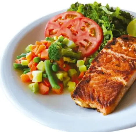 Plato con salmón a la plancha, arroz con verduras, jitomate y lechuga; representa una comida balanceada con los tres grupos de alimentos.