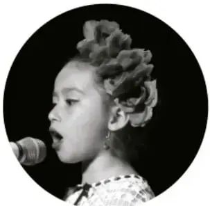 Fotografía en círculo de una niña hablando o cantando frente a un micrófono