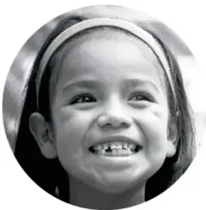 Fotografía en blanco y negro de una niña sonriente con banda en el cabello, en formato circular.