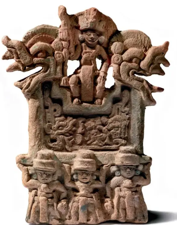 Escultura de cerámica de un silbato prehispánico con una figura humana sentada en lo alto, flanqueada por dos serpientes con doble cabeza, sobre una estructura con inscripciones, y tres figuras de jugadores de pelota en la base; la pieza proviene de Petén, Guatemala.