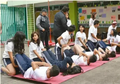 Fotografía de estudiantes realizando actividad física en colchonetas dentro de la escuela.
