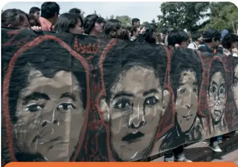 Protesta en la UNAM por los 43 desaparecidos en Ayotzinapa. Se observan rostros de los estudiantes en un mural.