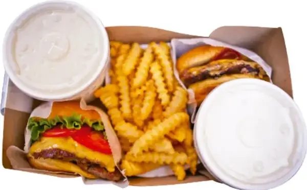 Fotografía de una comida rápida: hamburguesas, papas fritas, bebidas y aderezos.