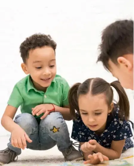 Foto de tres niños sentados en el piso conversando y trabajando en equipo, ilustrando el diálogo en la pequeña comunidad.