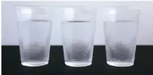 Tres vasos de plástico transparentes con agua, que ilustran el paso 1 de disolver la sal.