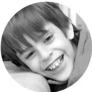 Fotografía en blanco y negro de un niño sonriente, como ejemplo de estudiante que participa en la exposición.