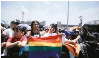 Grupo de jóvenes en una marcha con una bandera multicolor, ilustrando la valoración de creencias y pensamientos ajenos.