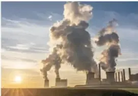 Fotografía de chimeneas industriales emitiendo humo al ambiente al atardecer.