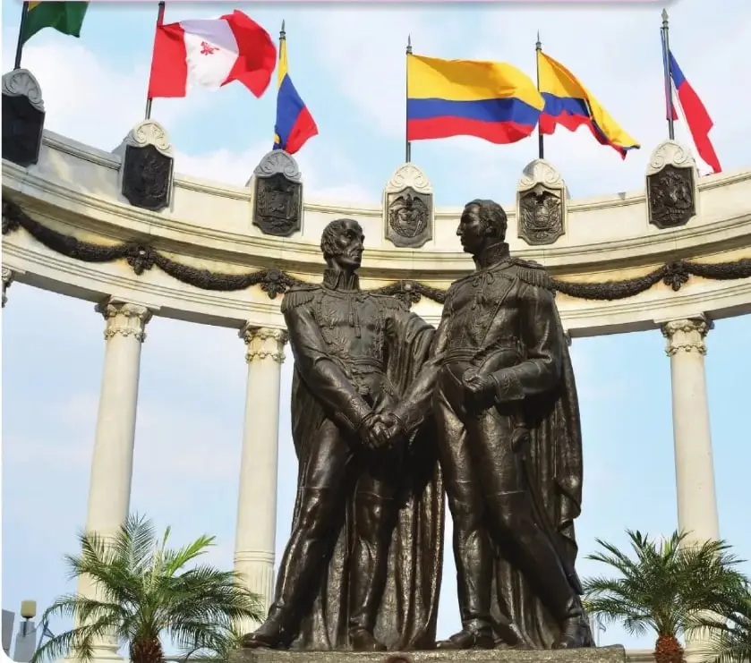 Fotografía del monumento de Simón Bolívar y José de San Martín en la Plaza Cívica de Guayaquil, rodeado de banderas y columnas.