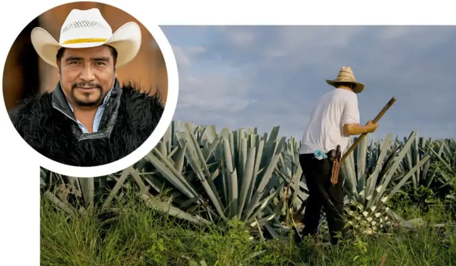Retrato circular de un hombre con sombrero blanco de ala ancha y chamarra de textura oscura, sonriendo.