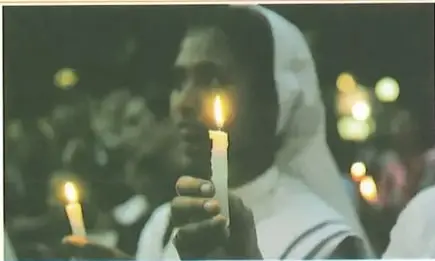 Persona sosteniendo una vela durante una actividad religiosa cristiana.