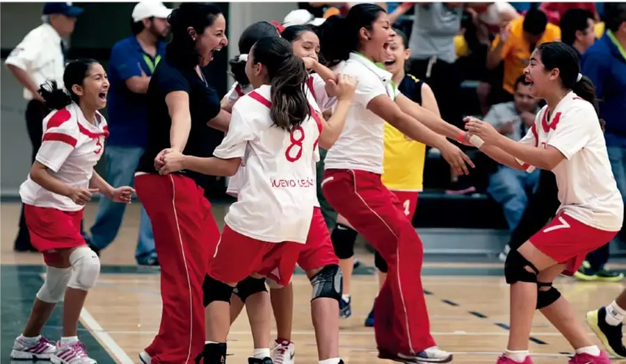 Fotografía de un equipo femenil de voleibol escolar (uniformes blancos y rojos, some
