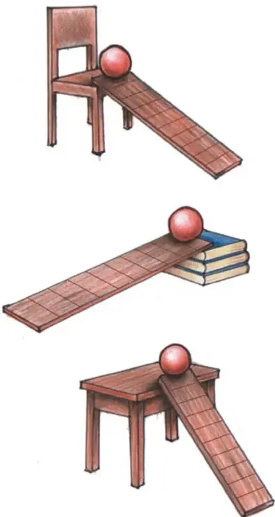 Tabla apoyada en un extremo sobre el asiento de una silla, con una pelota roja en la parte alta: resbaladilla de inclinación media.