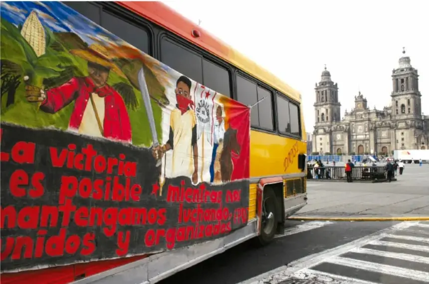 Fotografía de un autobús con mural que dice 'La victoria es posible mientras nos mantengamos luchando, unidos y organizados', frente a la Catedral Metropolitana de la Ciudad de México.