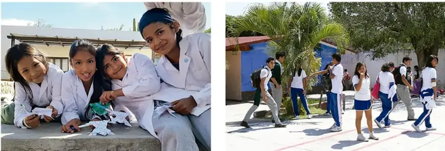Cuatro estudiantes de secundaria con uniforme blanco, sonrientes, reunidas alrededor de una mesa con materiales, colaborando en un proyecto.