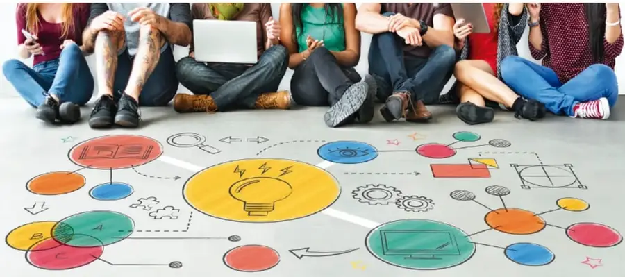 Grupo de jóvenes sentados en el suelo usando laptops y teléfonos; frente a ellos hay un dibujo colaborativo con íconos de ideas, engranajes, redes y formas geométricas que representan la conexión digital y el trabajo en equipo.