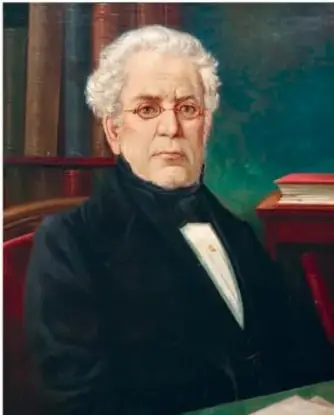 Retrato pictórico de Lucas Alamán, hombre mayor de cabello blanco, con traje oscuro y corbatín, junto a libros.