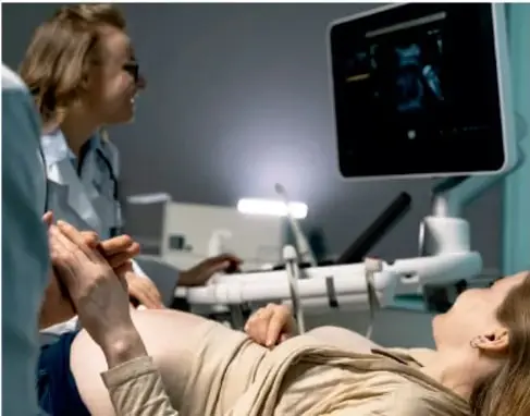 Consulta médica: una especialista realiza un ultrasonido a una paciente embarazada mientras observa la imagen en un monitor.