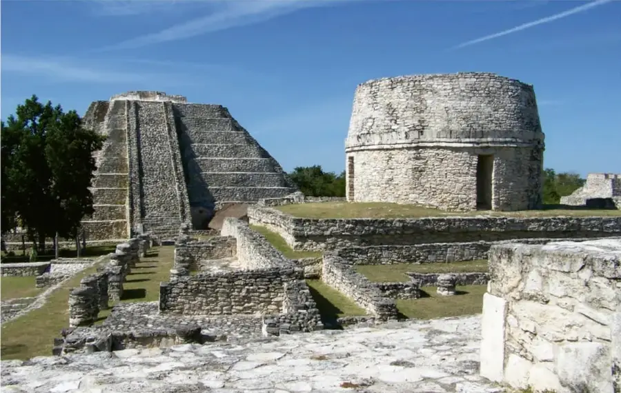 Zona arqueológica de Chichén Itzá con el templo piramidal de Kukulkán y el observatorio (El Caracol) bajo un cielo azul.