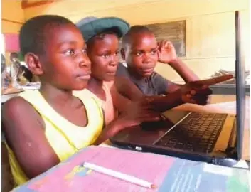 Varios niños utilizan una computadora en un espacio educativo. La imagen acompaña la idea de proteger los derechos y las creencias de todas las personas.