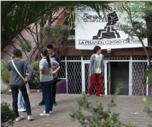 Grupo de jóvenes frente a un centro cultural con pancartas, participando en una actividad comunitaria.