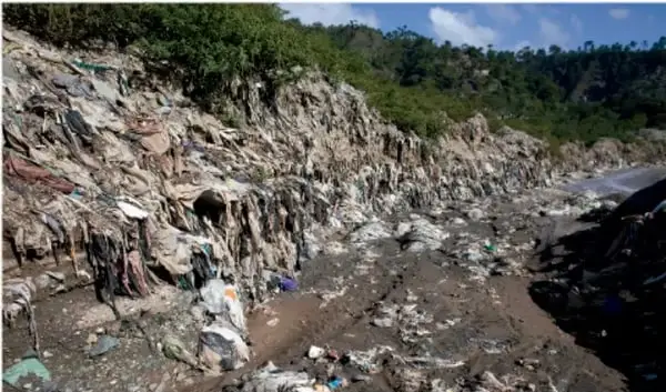 Fotografía de un vertedero a cielo abierto con gran acumulación de residuos sólidos en una ladera, ilustrando la contaminación ambiental.